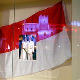 Der feierlich erleuchtete Palast reflektiert in einem Schaufenster, in dem zu Ehren der Thronfolger-Geburt ein Foto von Fürstin Charlène und Fürst Albert hängt.