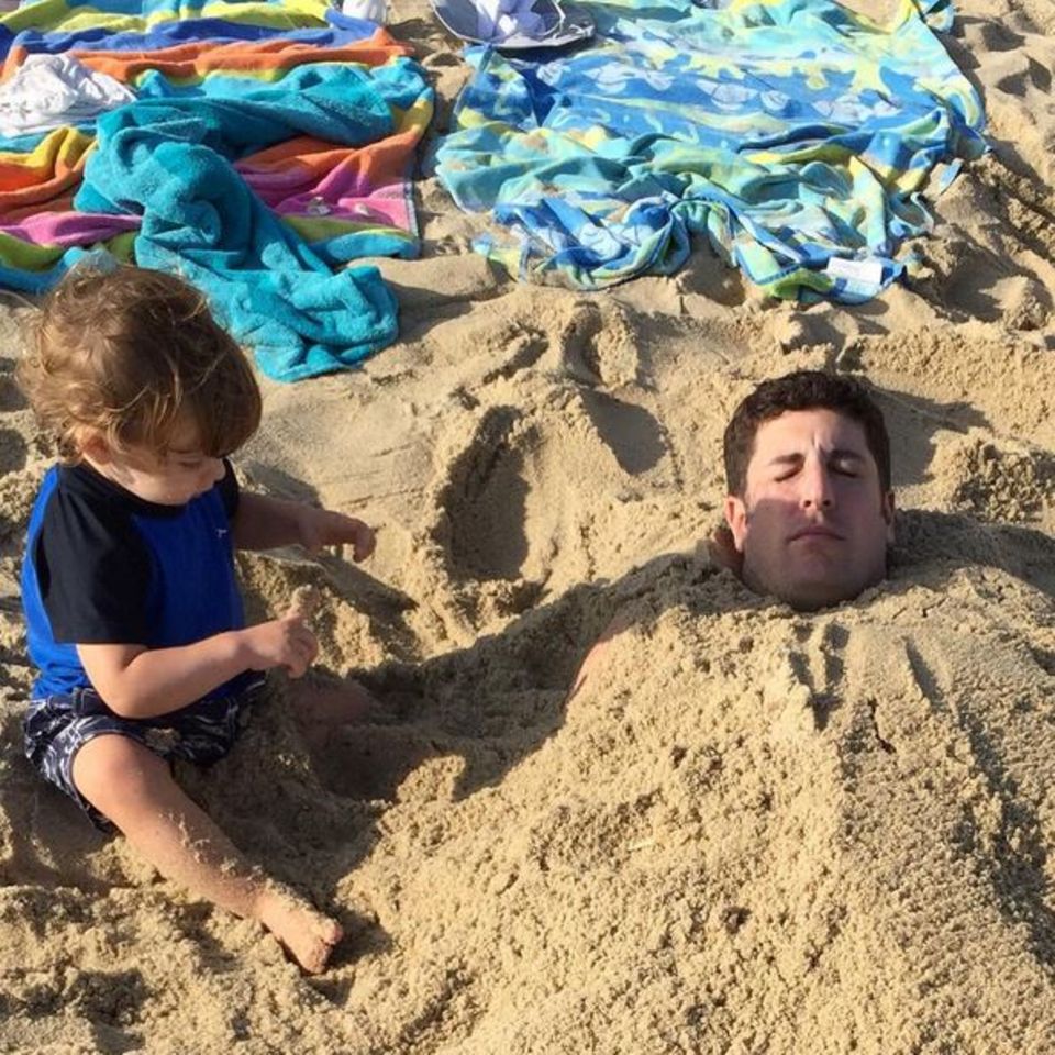 August 2015 Jason Biggs lässt sich von seinem Sprössling im Sand einbuddeln. August 2015 Jason Biggs lässt sich von seinem Sprössling im Sand einbuddeln.