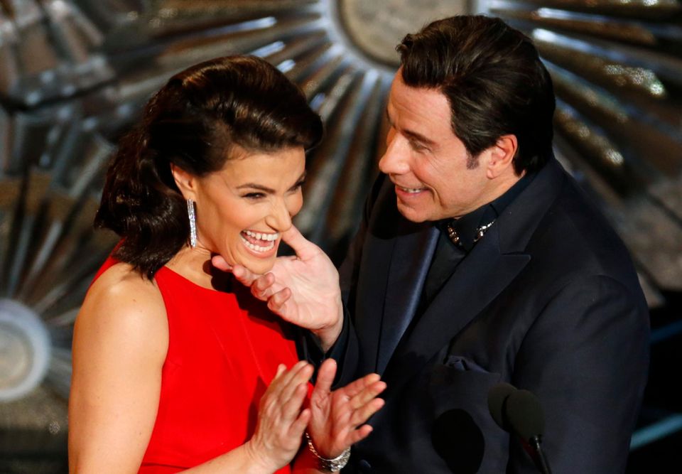 Damit es nicht wieder zu Versprechern kommt, kündigt dieses Mal Idina Menzel John Travolta an, erlaubt sich dabei jedoch einen kleinen Scherz.