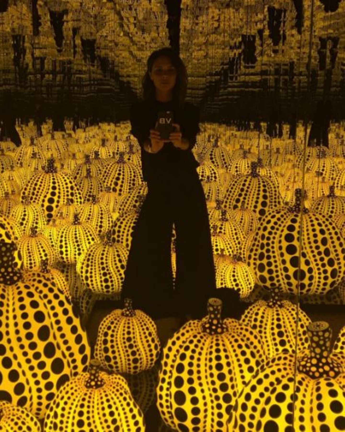 Victoria Beckham besucht in London eine Ausstellung der japanischen Künstlerin Yayoi Kusama und fotografiert sich inmitten von leuchtenden Kürbisskulpturen.