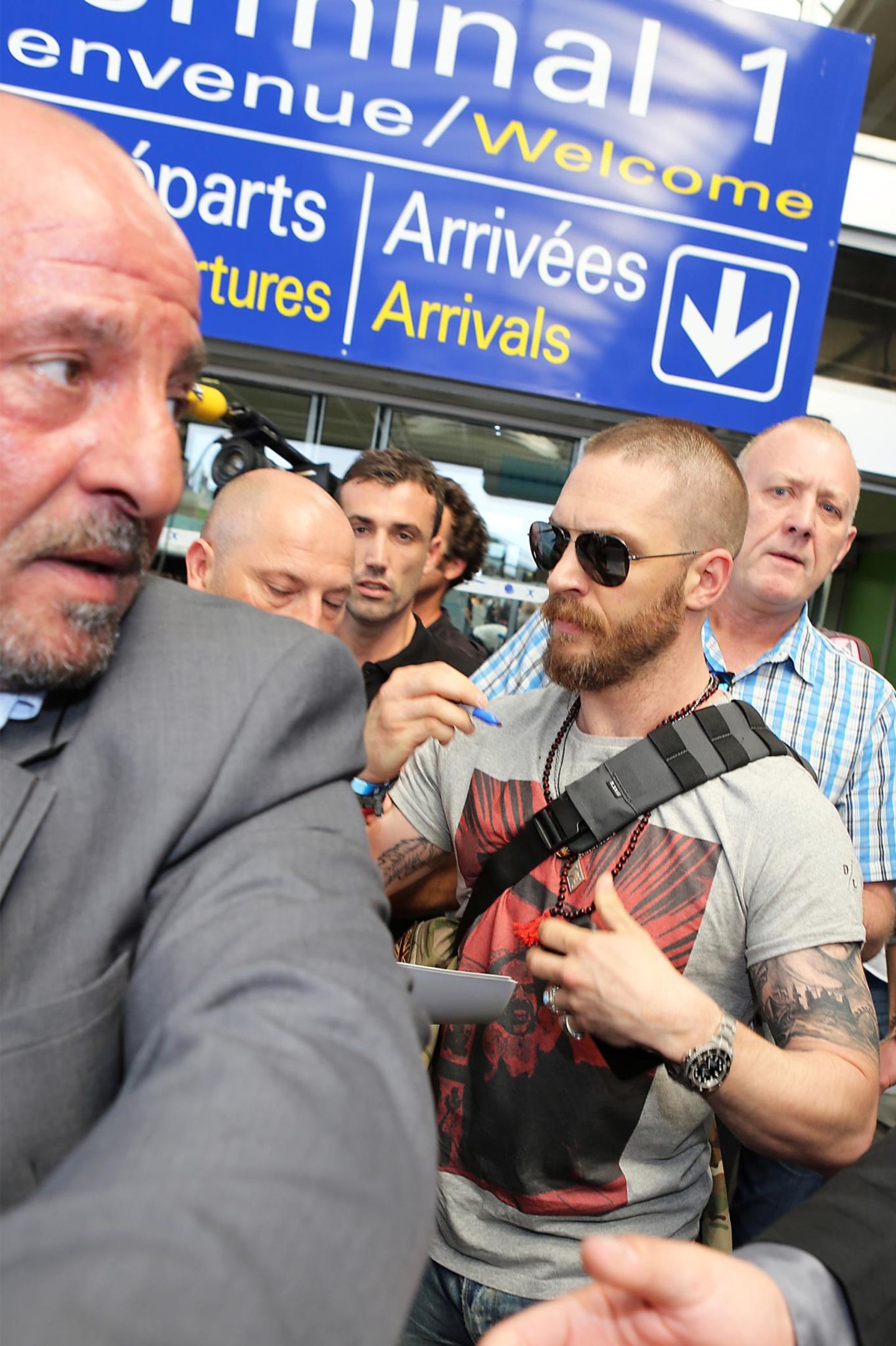 Schauspieler Tom Hardy kämpft sich am Flughafen durch die Massen und gibt noch schnell ein paar Autogramme.