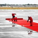 Tag 1  Regen in Berlin, ein paar Flughafenmitarbeiter rollen auf dem Flughafen Tegel in Berlin schon mal den roten Teppich auf dem nassen Boden aus.