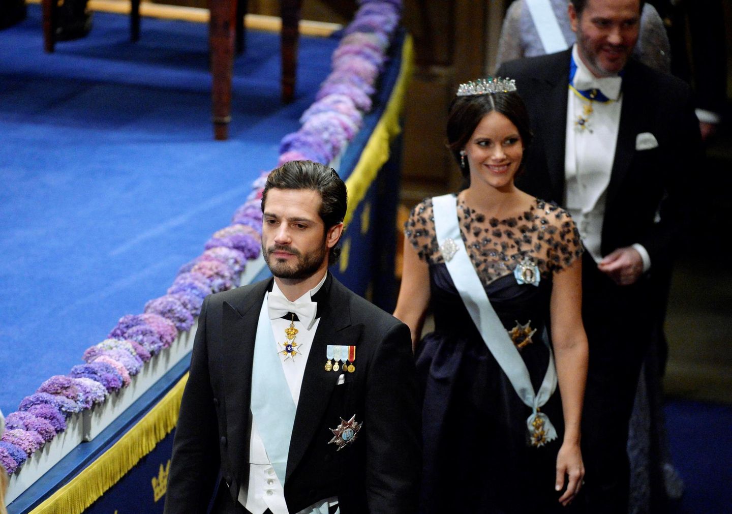 Prinz Carl Philip schaut sehr ernst, seine Frau Sofia, für die es die zweite Teilnahme an der Zeremonie ist, lächelt in die Runde.