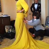 Eine Pop-Diva wie Jennifer Lopez zupft ihr atemberaubendes Kleid natürlich nicht selbst zurecht. Den kanariengelben Entwurf von Giambattista Valli Couture bringt eine Assistentin in Form.