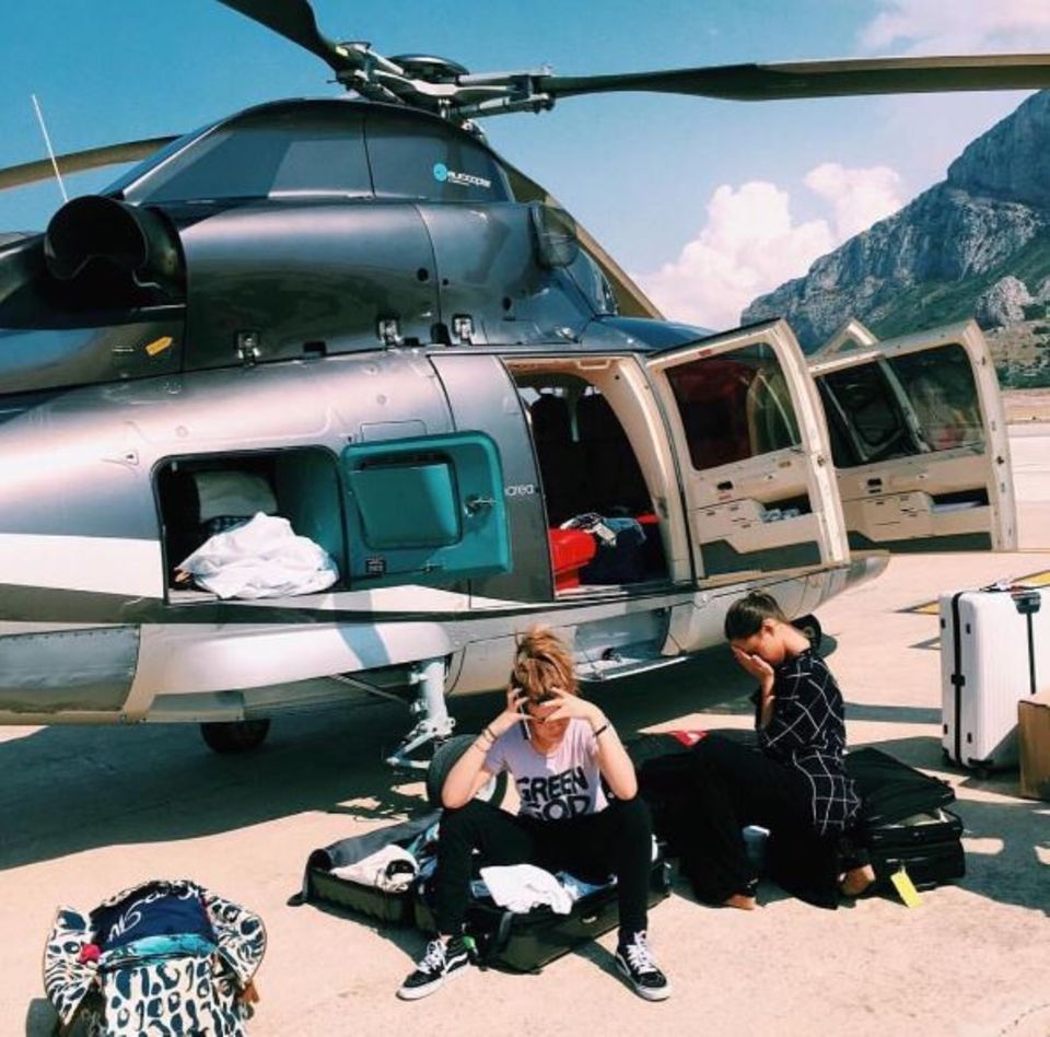 Sofia Richie sitzt auf einem offenen Koffer, den Kopf in die linke Hand gestützt, mit Smartphone in der Rechten telefonierend - dahinter eine kniende Frau, das Gesicht in den Handflächen vergraben. Im Hintergrund ist ein Hubschrauber zu sehen, dessen Türen und Verstaumöglichkeiten sperrangelweit offen sind. So viel Spielraum für Interpretationen!