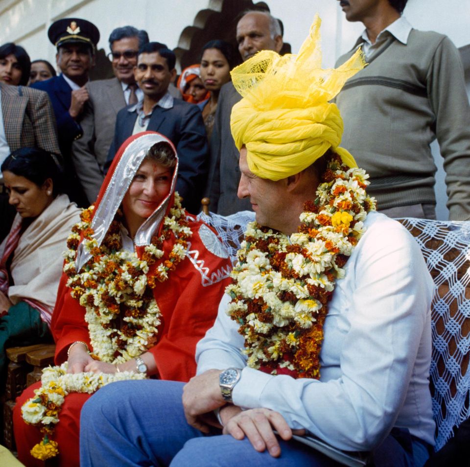 Als Königin Sonja und König Harald von Norwegen in 1986 Indien besuchen, lassen sie sich von den Einheimischen ganz landestypisch in Blumenkränze, Sari und Turban hüllen. Als Königin Sonja und König Harald von Norwegen in 1986 Indien besuchen, lassen sie sich von den Einheimischen ganz landestypisch in Blumenkränze, Sari und Turban hüllen.