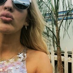 Ellie Goulding gewährt uns aus dem mit Wohnwagen ausgestatteten Künstler-Bereich eine Nahaufnahme auf ihr glamouröses Pailletten-Top und die schicke Fendi-Sonnenbrille.
