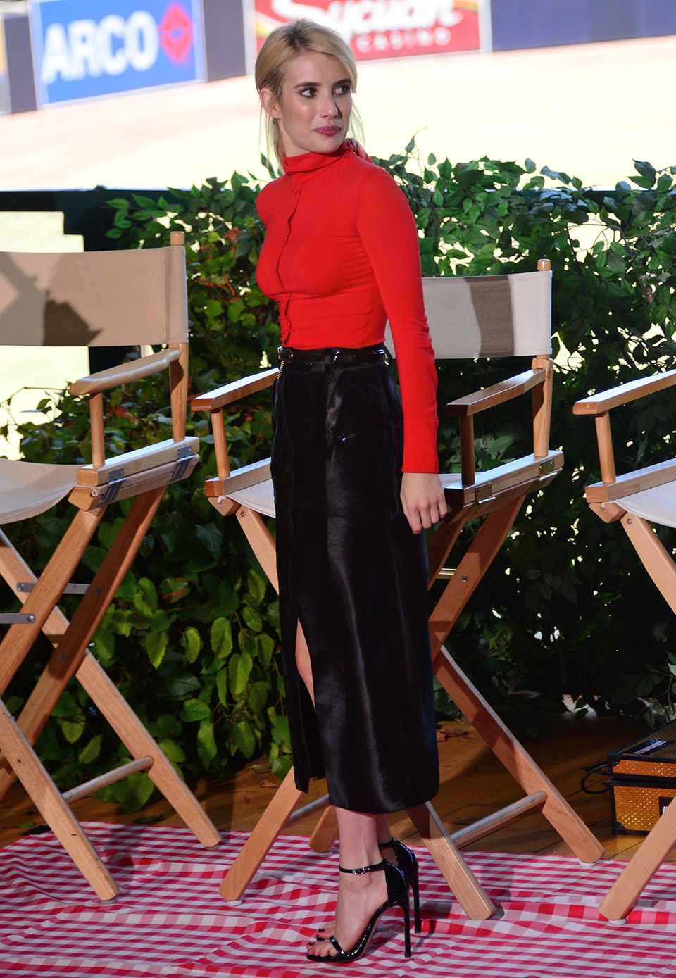 Emma Roberts ist mit leuchtend roter, knallenger Bluse, schwarzem Bleistift-Rock und hohen Stilettos ein richtig eleganter Blickfang.