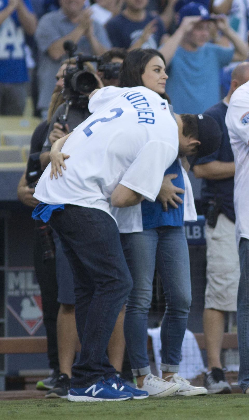 Auf dem Spielfeld beim Spiel der Los Angeles Dodgers vs Chicago Cubs: Liebevoll küsst Ashton Kutcher den Babybauch seiner Mila.
