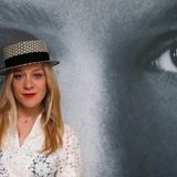 Schlicht mit Hut posiert Chloë Sevigny vor einem Schwarzweiß-Plakat. Sie ist zu einer Veranstaltung von "Kering Women in Motion" eingeladen.