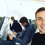Mario Götze strahlt iim Flieger in die Kamera und fotografiert nicht nur sich, sondern auch Teamkollegen Thomas Müller, der vertieft eine Zeitschrift liest.