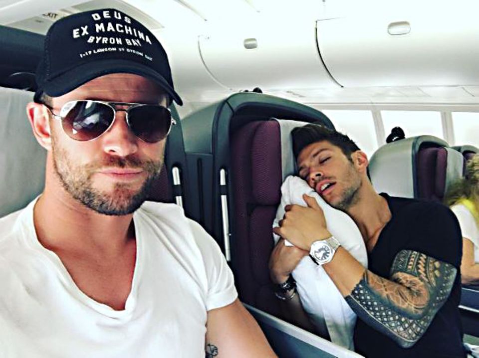 November 2016   Chris Hemsworth sitzt mit seinem Trainer Luke Zocchi im Flieger. Der hat sich in seinem Sitz eingekuschelt und schläft tief und fest, während sich Chris ironisch für die gute Unterhaltung bedankt.