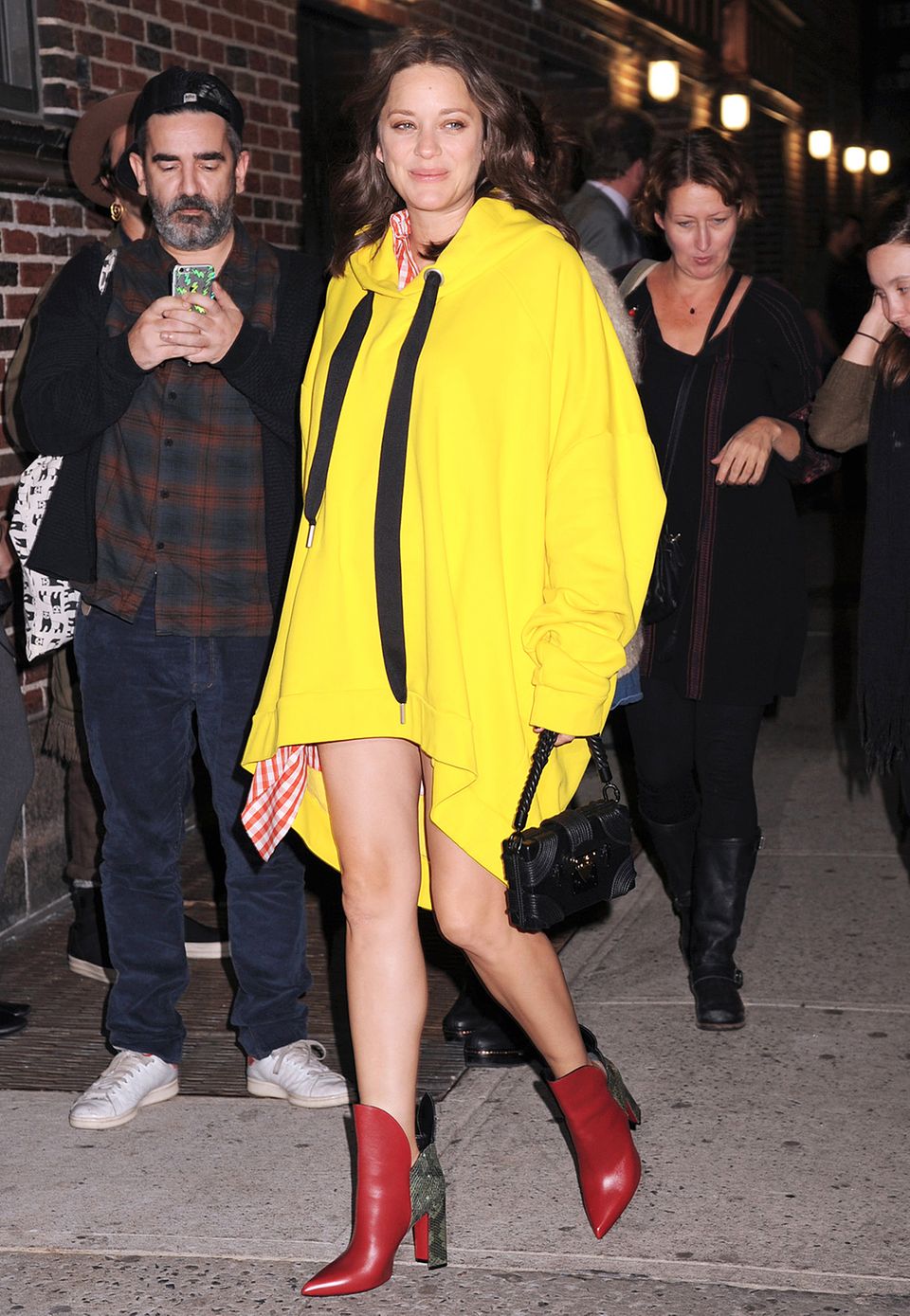 Mit ihrem neongelben Sweatshirt-Kleid ist Marion Cotillard in abendlichen New York perfekt sichtbar.