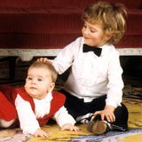 Weihnachten 1982 herrscht gute Laune. Prinz Carl Philip tätschelt Schwesterchen Madeleine des Kopf, Prinzessin Victoria lacht in die Kameras