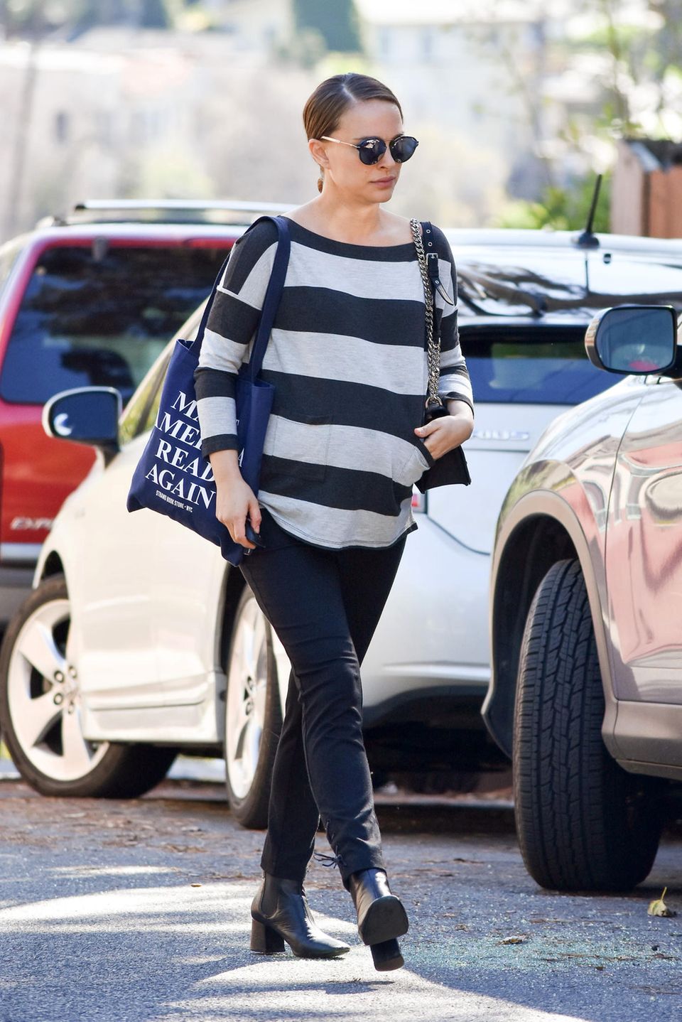 Lässig bis zur Geburt: Die hochschwangere Natalie Portman trägt zum locker fallenden, gestreiften Sweater eine schmale Hose und schwarze Stiefeletten. Dazu kombiniert sie eine Statement-Tasche mit dem Aufdruck "Make America Read Again". Ob sie wohl Bücher geshoppt hat?