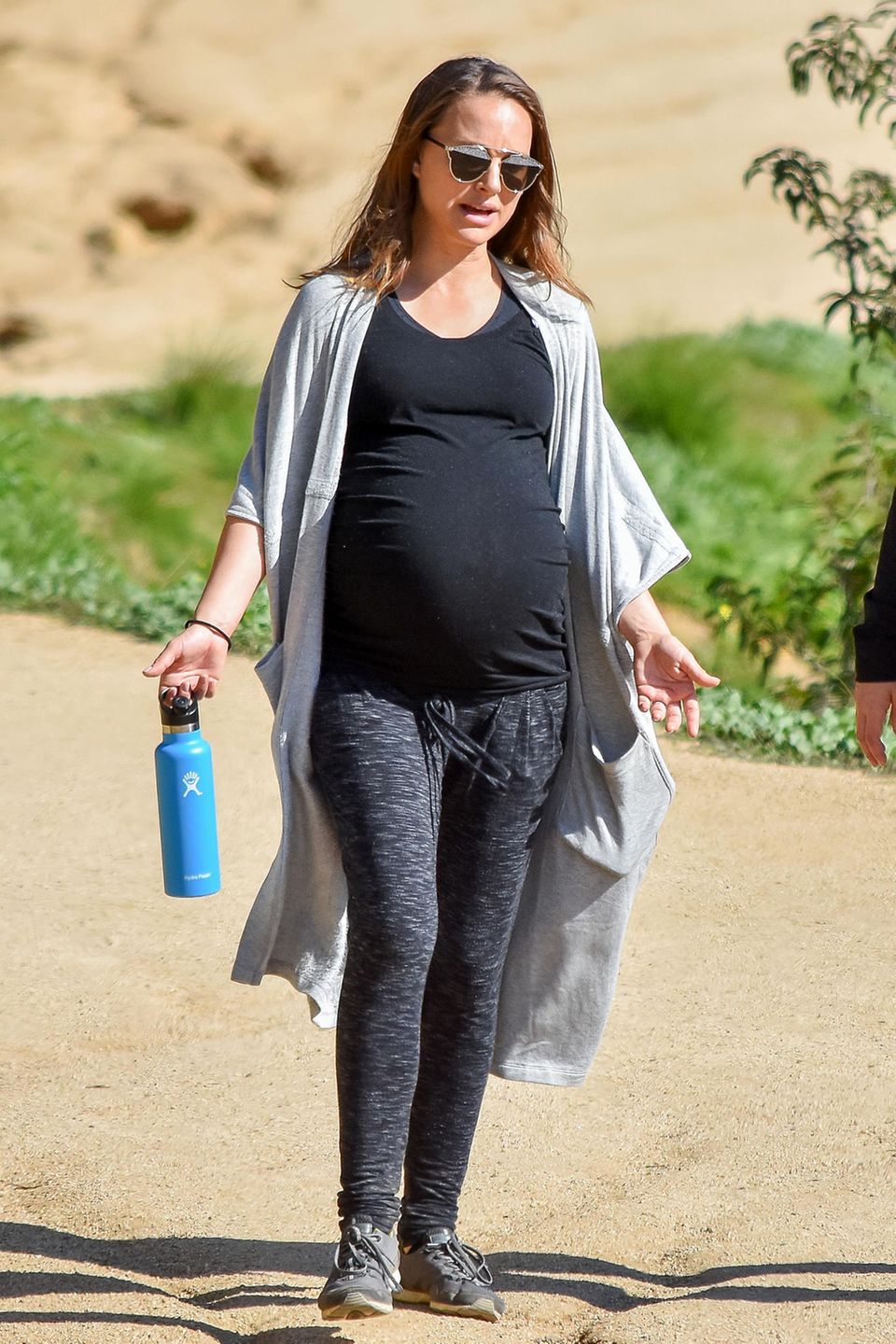Dass sie jederzeit ihr Baby kriegen könnte, hält Natalie Portman nicht davon ab, einen ausgedehnten Hike zu unternehmen. Ihr Outfit ist dementsprechend sportlich und bequem: Zur anthrazitfarbenen Leggings kombiniert sie ein schwarzes Top, einen luftigen Cardigan und eine stylishe Sonnenbrille. Natürlich darf auch die Wasserflasche nicht fehlen.