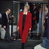 Auf ihrer Reise in die Schweiz wählt Prinzessin Diana einen langen roten Mantel mit sichtbaren Knöpfen. Dazu kombiniert sie eine schwarze Hose sowie einen schwarzen Pullover mit weißem Bubi-Kragen. 