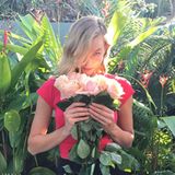 Model Karlie Kloss schnuppert an einem Strauß Rosen.