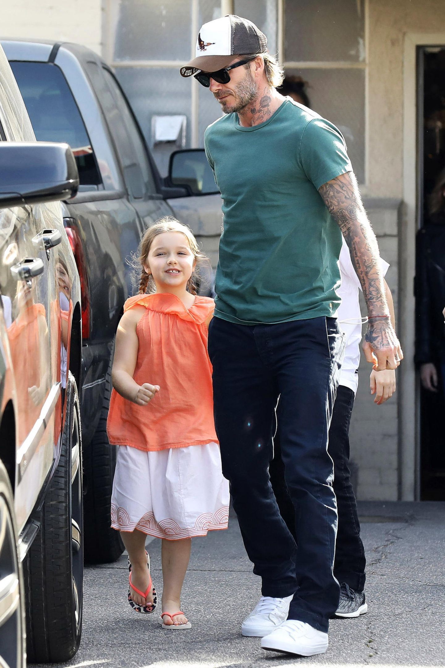 Kleine Grinsekatze! Gut gelaunt zeigt sich Harper an der Seite von Papa David in sommerlichem Look. In Beverly Hills kann man auch schon schicke Leo-Flip-Flops tragen.