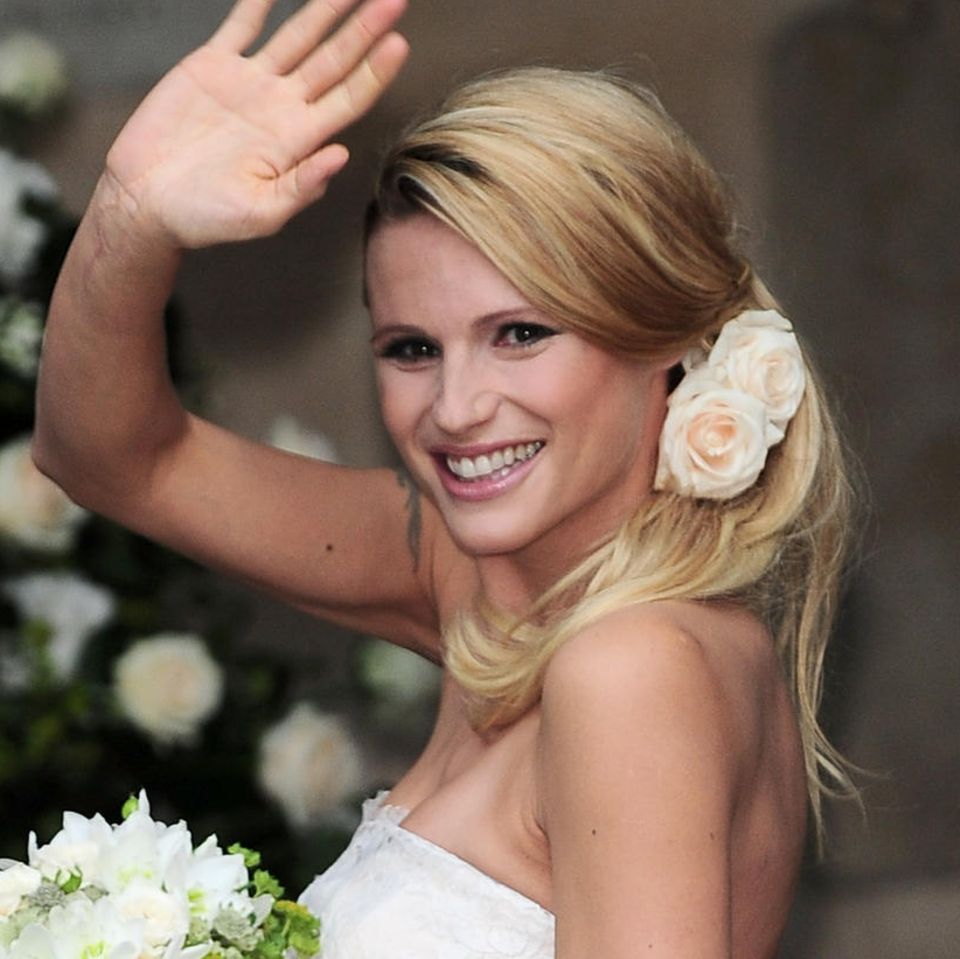 Michelle Hunziker verwandelt sich an ihrem Hochzeitstag in eine besonders romantische Braut. Dafür sorgen in erster Linie die Rosen, die ihre seitliche One-Shoulder-Frisur verzieren. Das Volumen im Ansatz lässt sie außerdem natürlich erscheinen.