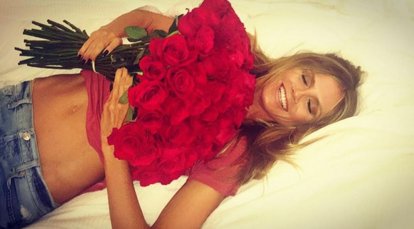 Für mich soll's rote Rosen regnen: Heidi Klum lässt sich freudestrahlend mit einem riesigen Blumenstrauß ins Bett fallen.  