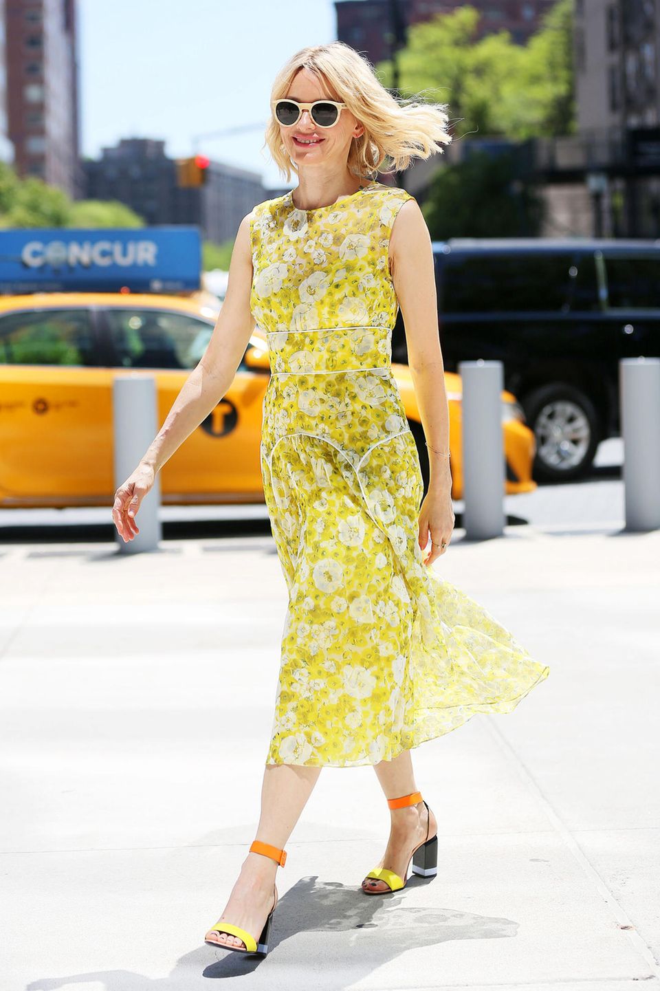Endlich ist der Sommer Da! Und Naomi Watts feiert ihn in New York mit diesem strahlend gelben Blumenkleid und farblich toll passenden High Heels.