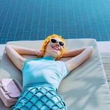 Türkisfarbener Stretchbody und strassverzierter Gitterrock von Elisabetta Franchi. Handtasche "Double T Mini" von Tod's. Cateye-Sonnenbrille von Dolce & Gabbana