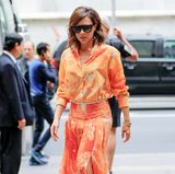 Ein sommerlich-stylischer Blickfang ist auch Victoria Beckhams leuchtend orangefarbene Ensemble aus luftiger Bluse und schön schwingendem Faltenrock.