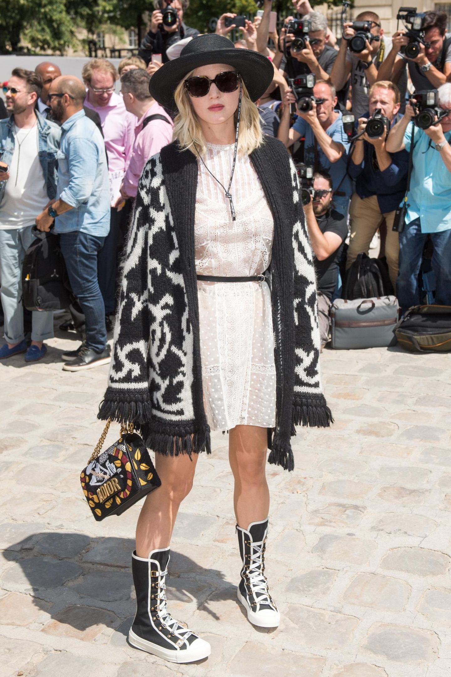 Was war denn da los, J.Law? Jennifer Lawrence präsentiert sich bei Dior mit Boxerstiefel und übergroßer Strickjacke im schwarz-weißen Lotter-Look.