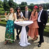 Neben den perfekt geschnittenen Buchsbaumgärten sind weiße Stehtische aufgestellt, an denen die Gäste ihren Champagner genießen können.