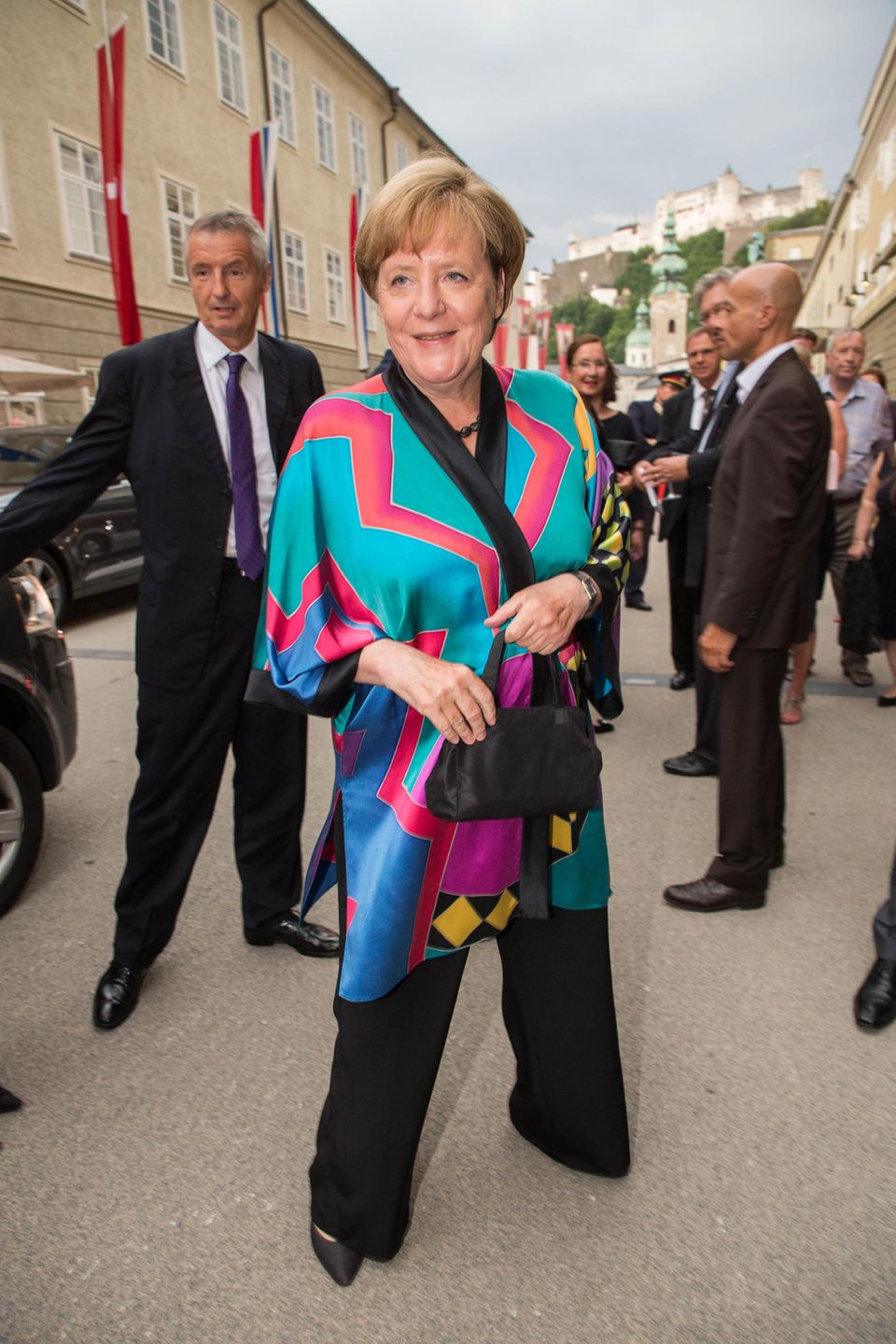 Bei den Salzburger Festspielen zeigt sich Angela Merkel in diesem Jahr ungewohnt farbenfroh. Für die Premiere von "Lady Macbeth von Mzensk" hat sich die Bundeskanzlerin für diesen auffälligen Seiden-Kimono entschieden, den sie mit schwarzer Hose kombiniert. Bei den Salzburger Festspielen zeigt sich Angela Merkel in diesem Jahr ungewohnt farbenfroh. Für die Premiere von "Lady Macbeth von Mzensk" hat sich die Bundeskanzlerin für diesen auffälligen Seiden-Kimono entschieden, den sie mit schwarzer Hose kombiniert.