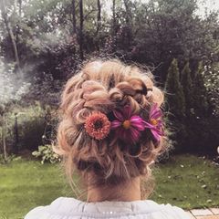 Dreht sich Monica um, entpuppt sich ihre Frisur jedoch als haariges Meisterwerk. In ihre eng anliegenden Zöpfe wurden sogar frische Blumen eingearbeitet.
