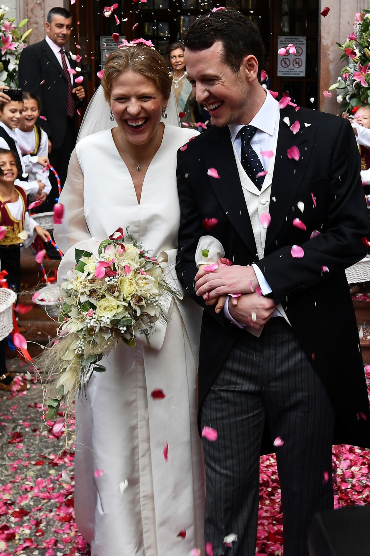 Vor der Kathedrale erwartet das frisch vermählte Ehepaar ein Regen aus Rosenblättern. Jetzt können sie so richtig strahlen und ihr Glück erstmals fassen.