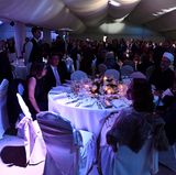 Die Gäste sitzen während der Feier an großen runden Tischen, der Raum ist mit einem Baldachin ausgekleidet und in blaues Licht getaucht. Die romantische Atmosphäre entsteht durch Kerzenschein  und Rosengedecke.