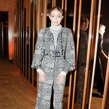Topmodel Gigi Hadid trägt einen grau-weißen Wollmantel mit auffälliger Chanel-Schnalle. Dazu trägt sie silberne Metallic-Boots und einen Rollkragen-Pullover. 