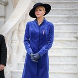 Am Nationalfeiertag Monacos sticht Fürstin Charlène vor den weißen Marmorstufen des Palastes in ihrem blauen Mantel von Akris wundervoll hervor. Der samtige Stoff wirkt dabei besonders royal.