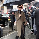 Auf dem Weg zu ihrer eigenen Fashion-Show schützt sich Victoria mit Schirm und elegantem, grau-khakifarbenem Mantel vor dem New Yorker Mistwetter.