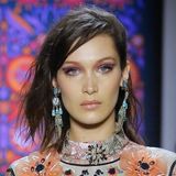 Auf dem Runway der "Anna Sui"-Show in New York wird es farbenfroh und verspielt. Topmodel Bella Hadid trägt mehrfarbigen Lidschatten, auffällige Ohrringe und wildes Haar. 