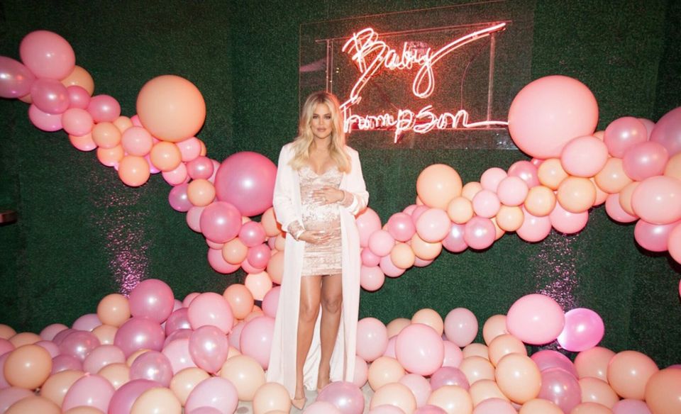 Die überglückliche Khloé Kardashian präsentiert sich strahlend schön umzingelt von etlichen, pinken Luftballons und einer Neon-Leuchtschrift mit den Worten "Baby Thompson". 