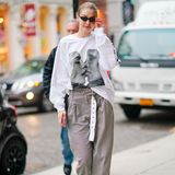 Das kurze Röckchen und die Lederstiefel tauscht Gigi zurück in New York gegen Chino-Hose und Sweatshirt ein. An die Liebe scheint sie dennoch weiterhin zu glauben; auf ihrem weißen Shirt ist ein Aufdruck ihrer sich küssenden Modelkolleginnen Cara Delevingne und Adwoa Aboah. 