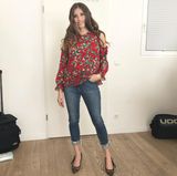 In einem sommerlichen Blüschen mit Cut-Outs an den Schultern und Jeans zeigt sich Cathy lässig und trotzdem feminin. Ihre langen Haare trägt sie in großen Wellen. 