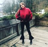 Ihre schwarze Jeans bezirzt durch besondere Volant-Details am Bein. Dazu kombiniert sie schwarze Ankle Boots und einen XL-Strickpulli in Rot. 