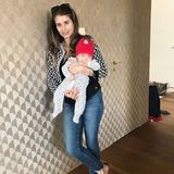 In dunkelblauer Jeans, gemustertem Cardigan und sommerlichen Sandalen scheint Cathy den Frühling einläuten zu wollen. Söhnchen Ludwig trägt dennoch ein rotes Mützchen zu seinem gemusterten Strampler. 