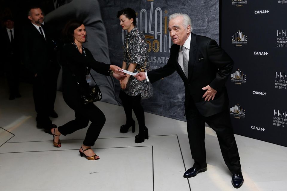 Mit einem Knicks, fast wie vor einem König, überreicht die Dame dem großen Regisseur Martin Scorsese einen Zettel.