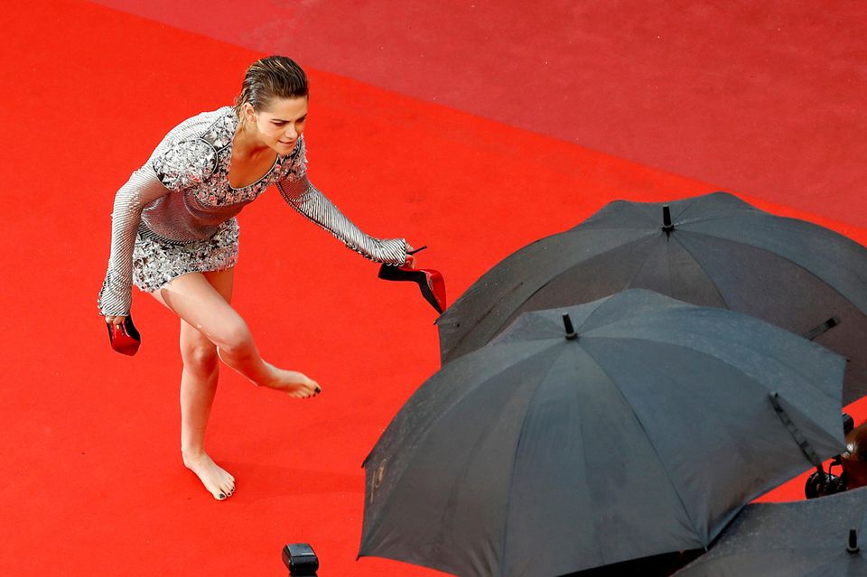 Hollywoodstar Kristen Stewart, Mitglied der Jury bei den Filmfestspielen, scheint die hohen Absätze leid zu sein und zieht ihre Pumps mitten auf dem roten Teppich aus.