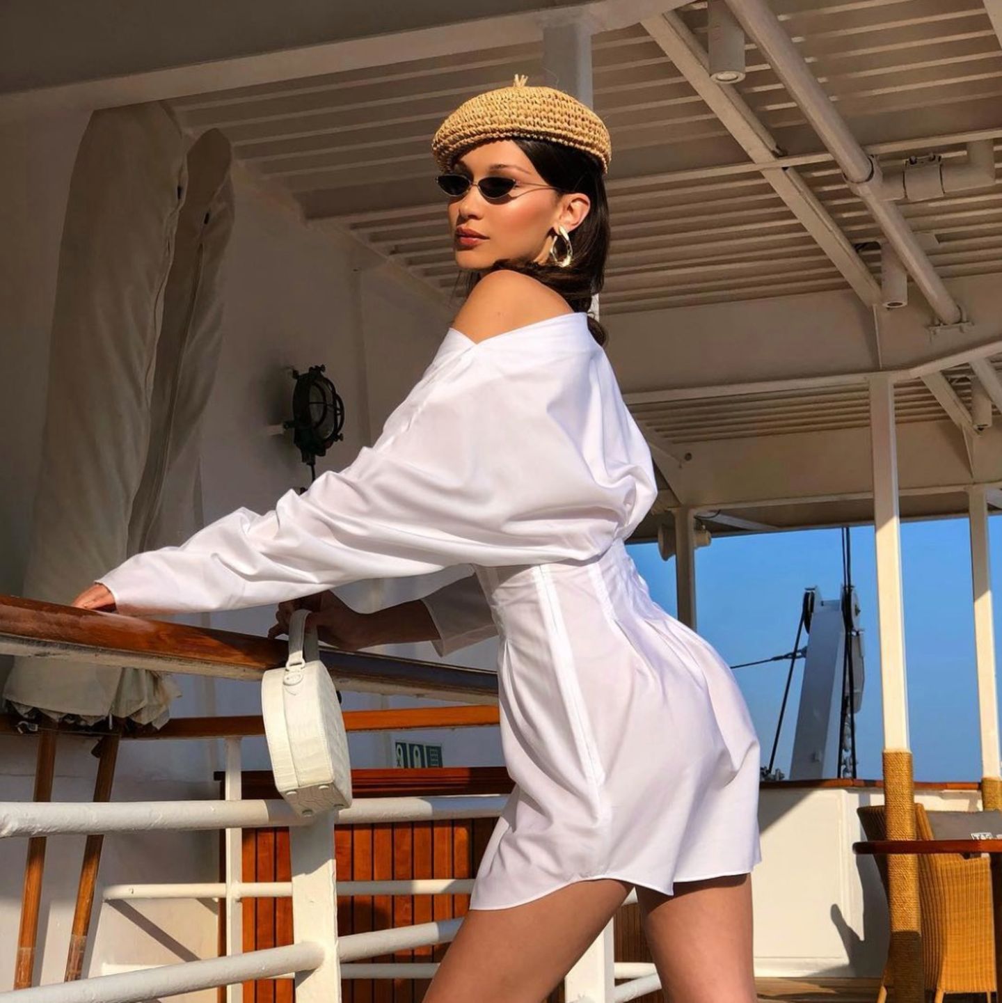 Der perfekte Look für einen Sommertag in Monaco: Bella Hadid entscheidet sich für ein dunkles, schmales Modell. Dazu trägt sie ein weißes Blusenkleid und einen Beret-Hut aus Stroh. 