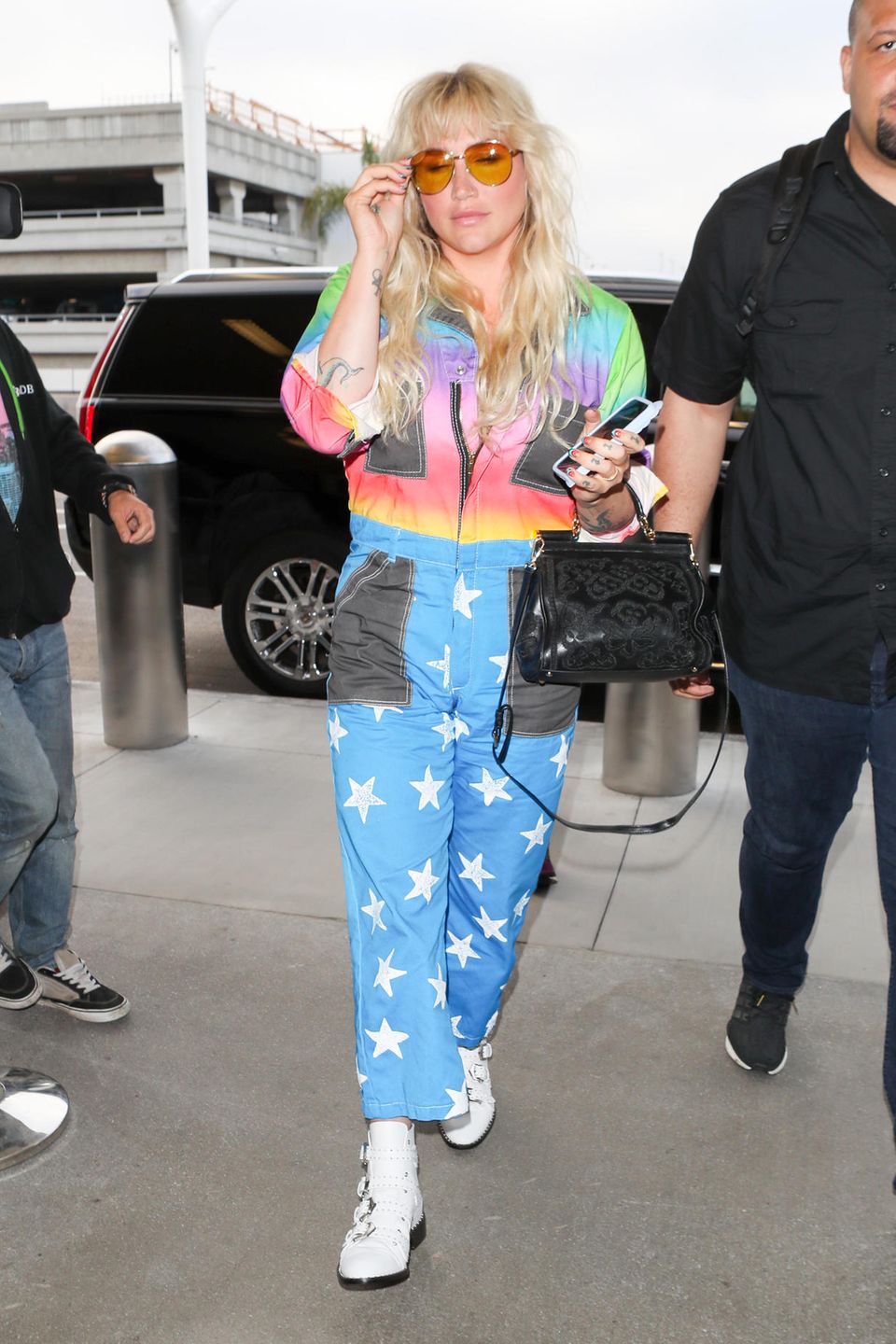 Auweia, was ist das nur für ein Overall, den Kesha hier am Flughafen trägt?! Da kann man nur hoffen, dass die Sicherheitsleute sie nicht weitergehen lassen und ihr den Rainbow-Space-Anzug direkt abnehmen.