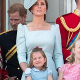 In einem blauen Kleid mit weißem Blumenmuster und Peter-Pan-Kragen zeigt sich Prinzessin Charlotte auf dem Balkon des Buckingham Palace – Ton in Ton mit Mama Herzogin Catherine. Besonders süß: Die rote Schleife im Haar der Dreijährigen.