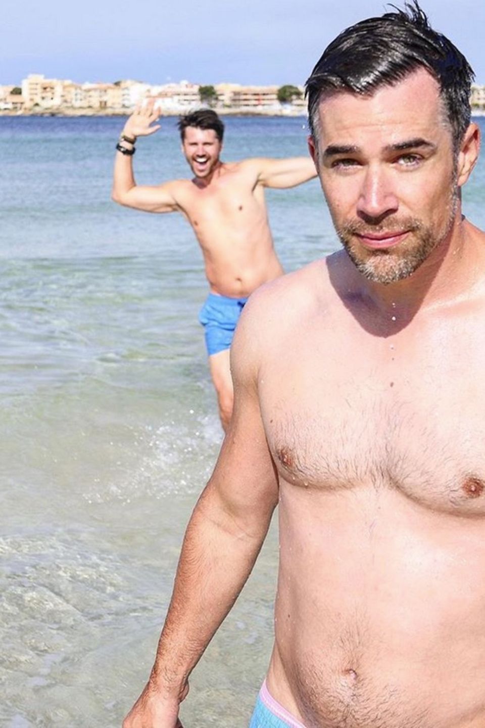 Schauspieler Jo Weil möchte am Strand von Mallorca ein schönes Selfie schießen. Schwupps, da springt Thore Schölermann im Hintergrund ins Bild. Ob Jo davon so begeistert ist?