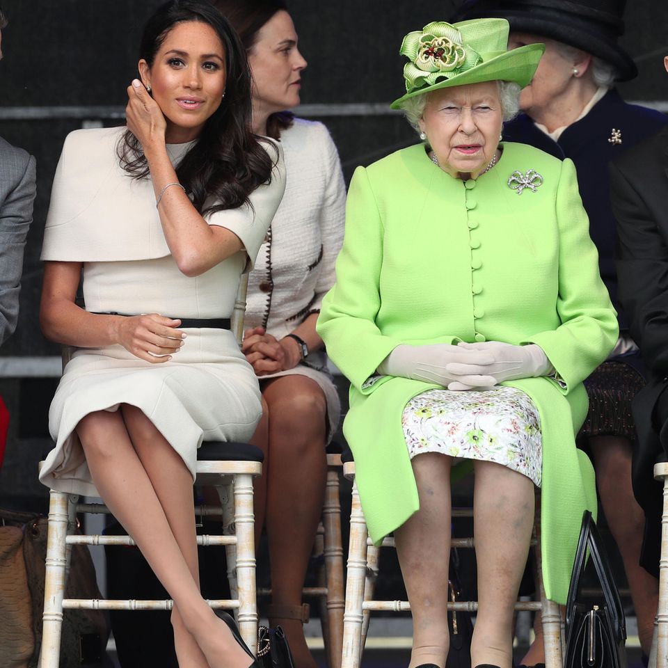Ist das ein Zeichen? Die Queen stellt neben Herzogin Meghan ihre Handtasche auf die linke Seite. Eigentlich wird nun das Personal in Alarmbereitschaft versetzt und soll die Königin aus der Situation retten.